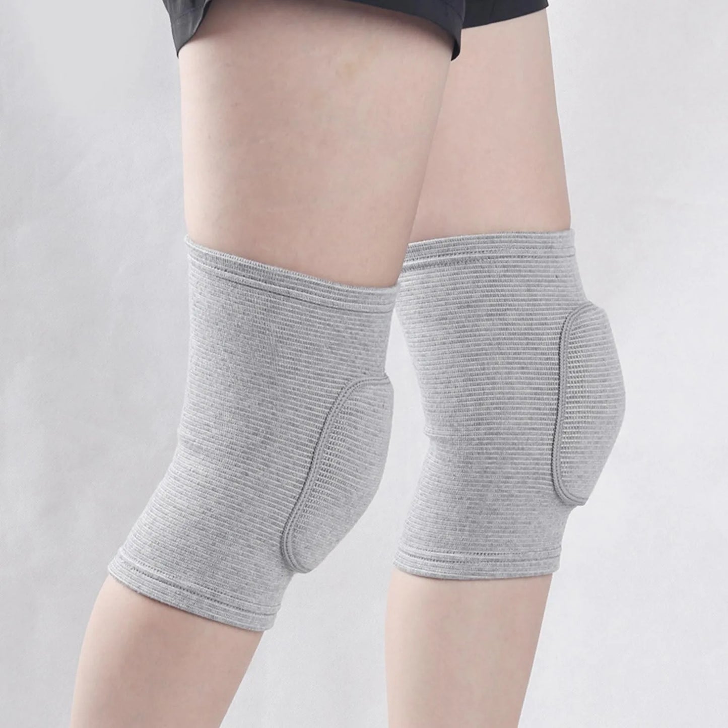 Grey closed knee pads with padded protection over knees, worn on legs, elastic fabric.