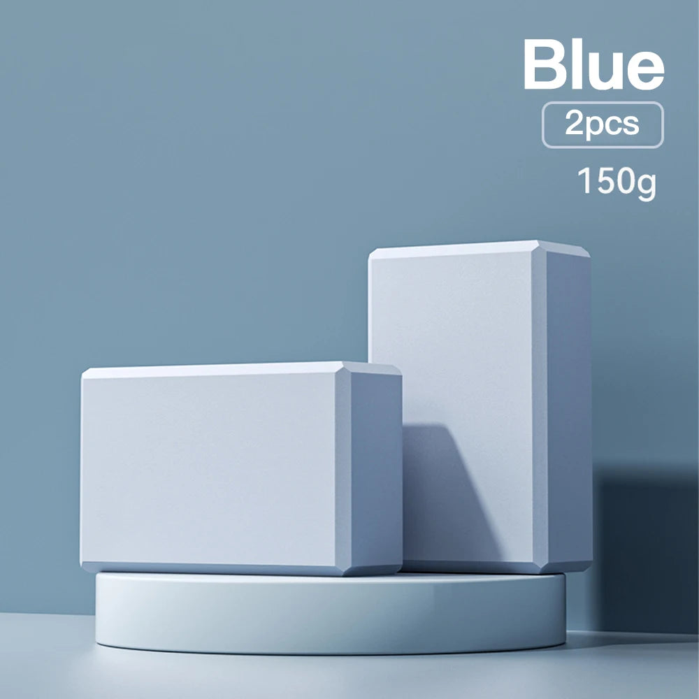 Two blue high-density foam yoga blocks on a blue display stand, indicating 'Blue, 2pcs, 150g'.